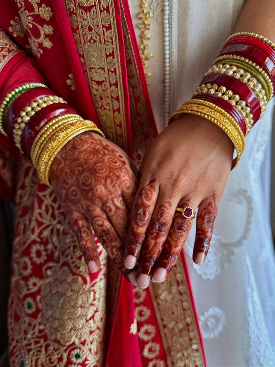 A bride's hands with fresh mehndi and gold and red bangles
